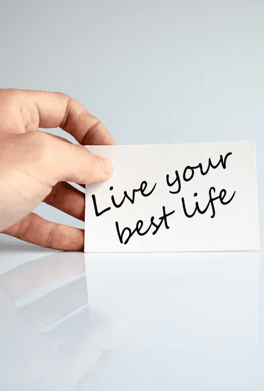 A hand holding a card that reads “Live your best life”